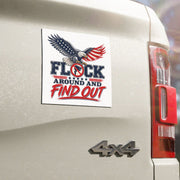 A square white sticker with a patriotic eagle graphic and the text 'FLOCK AROUND AND FIND OUT' in blue and red, shown applied to the rear side of a beige 4x4 truck outdoors.